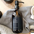 Black personalised label sticker on amber bottle for his body wash and a home collection text underneath.