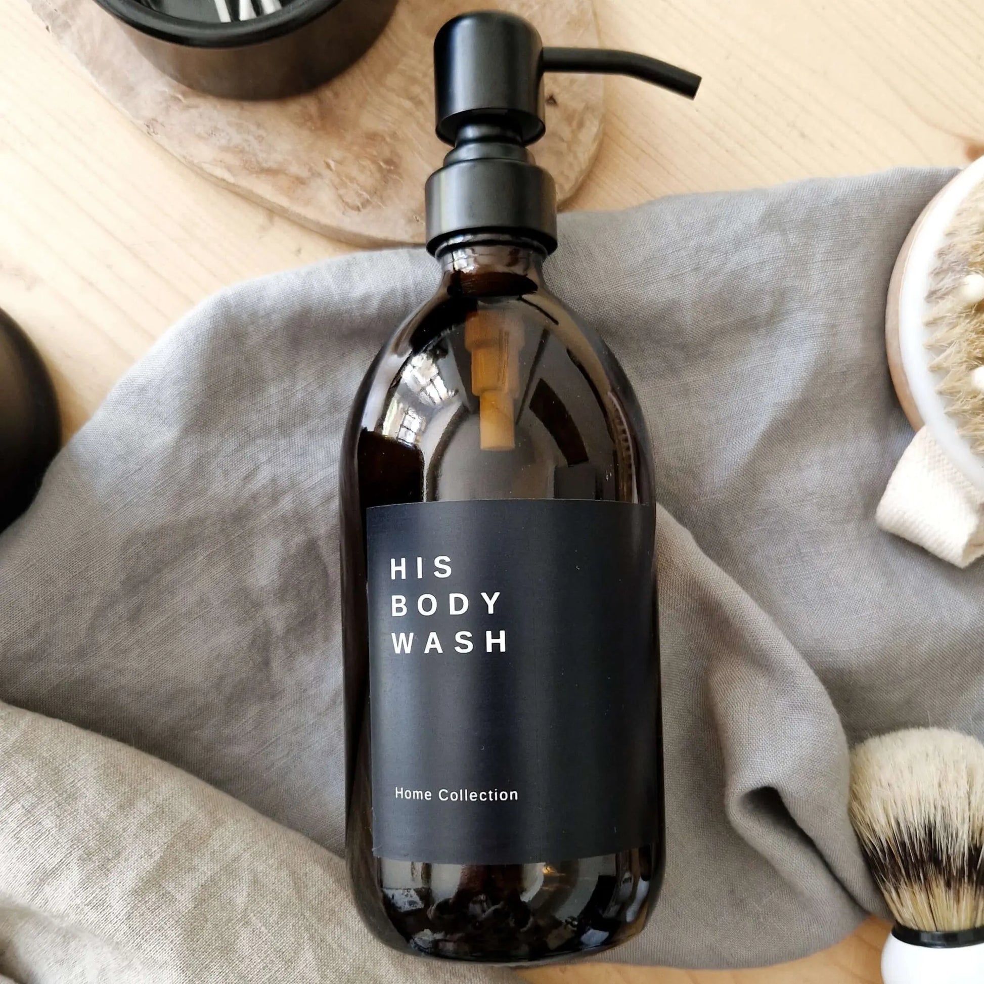 Black personalised label sticker on amber bottle for his body wash and a home collection text underneath.