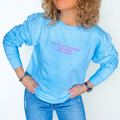 Person wearing a light blue sweatshirt with text 'Got my shit together just kidding pure chaos', standing against a white background