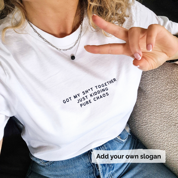 Person wearing a white t-shirt with text 'Got my shit together just kidding pure chaos' and making a peace sign.