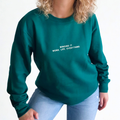 Person wearing a green sweatshirt with text 'winging it. Work, life, everything' on a plain background