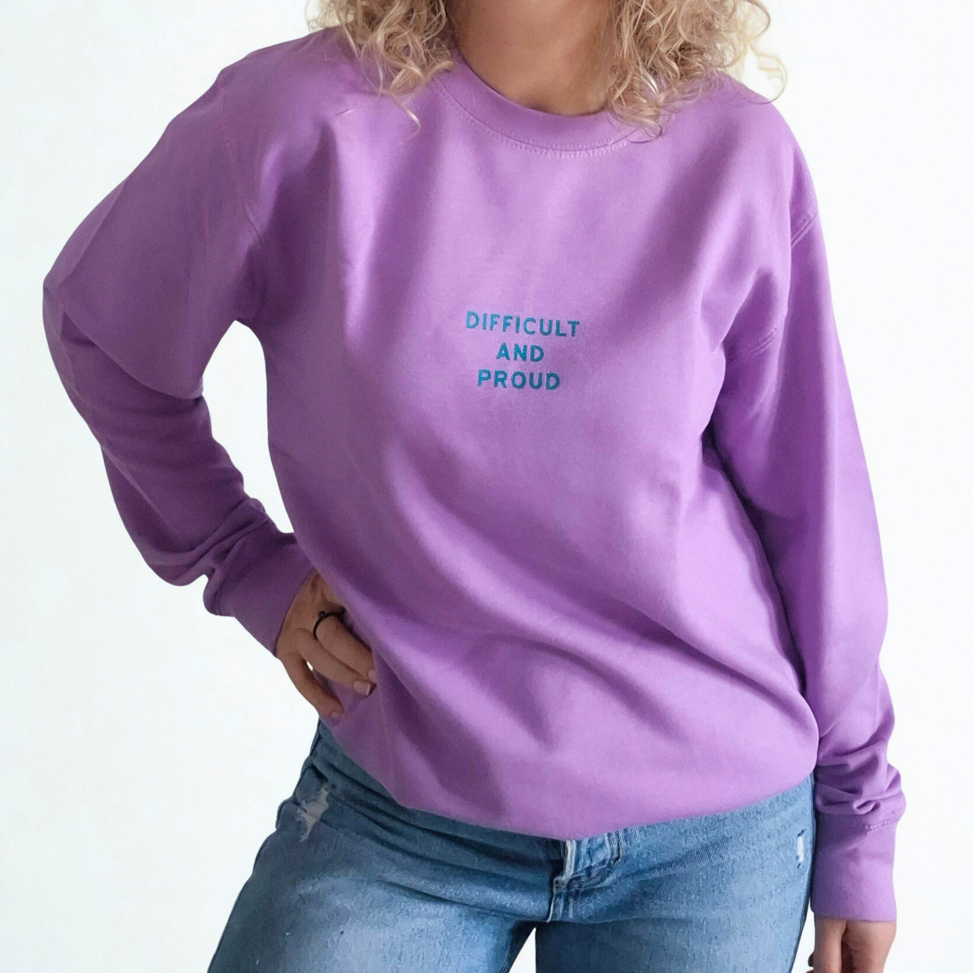 Person wearing a purple sweatshirt with 'DIFFICULT AND PROUD' text on a white background
