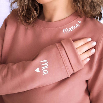 A personalised sweatshirt with a custom text on the neckline and names on the sleeve. The neckline text in white 'ama' and children's names on the sleeve