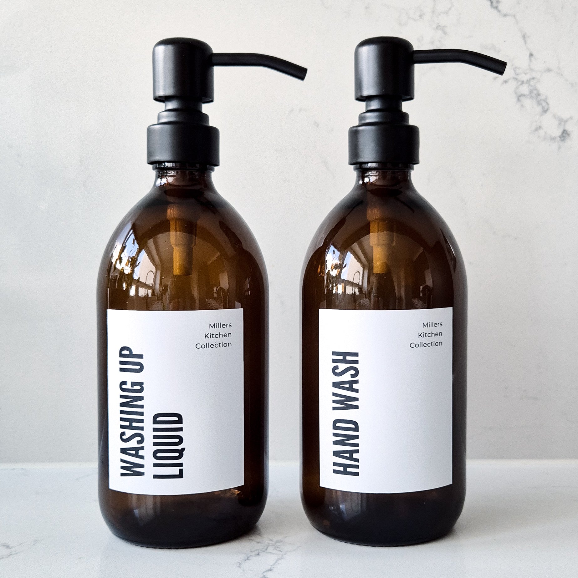 Two brown glass bottles with pump dispensers labeled 'Washing Up Liquid' and 'Hand Wash' on a light background.