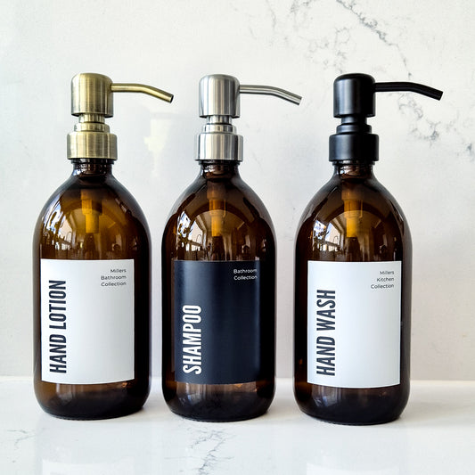 Three brown bottles labeled 'Hand Lotion', 'Shampoo', and 'Hand Wash' on a marble surface.