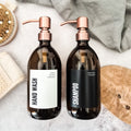 Two brown bottles with pump dispensers labeled 'Hand Wash' and 'Shampoo' on a neutral background.
