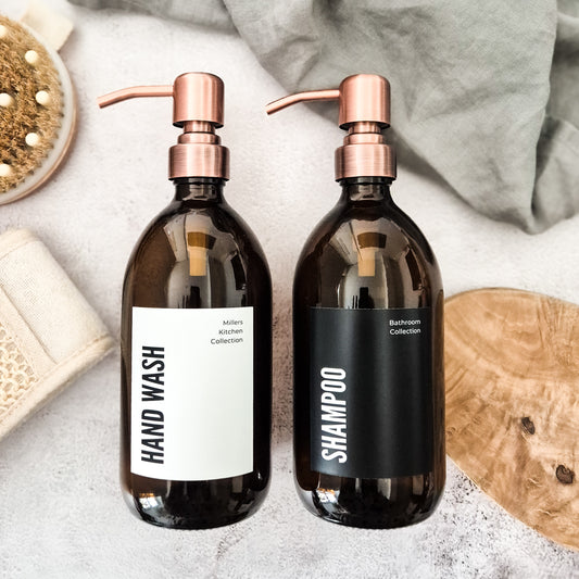 Two brown bottles with pump dispensers labeled 'Hand Wash' and 'Shampoo' on a neutral background.