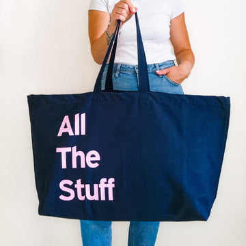 Large navy personalised tote bag with pink bold text reading All The Stuff, held in hand.