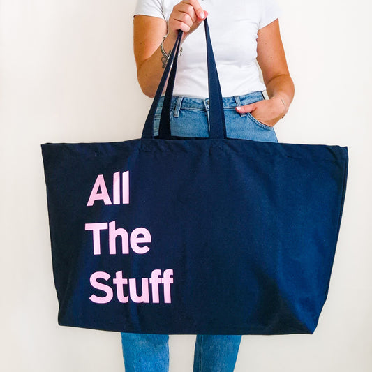 Large navy personalised tote bag with pink bold text reading All The Stuff, held in hand.