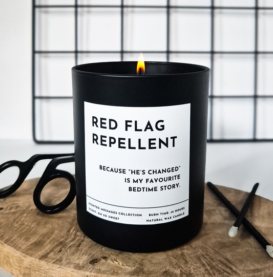 Black candle with bold white label reading Red Flag Repellent, funny breakup gift