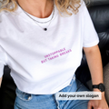 Person wearing a white t-shirt with pink text 'Unstoppable but taking breaks' and jeans, sitting on a black leather couch.