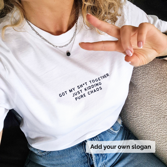 Person wearing a white t-shirt with text 'Got my shit together just kidding pure chaos'  and making a peace sign.