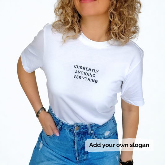 Person wearing a white t-shirt with text 'Currently avoiding everything' and blue jeans on a white background