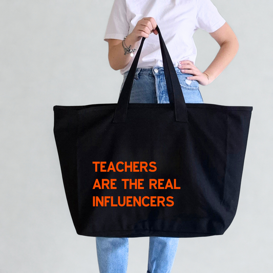 Person holding a black tote bag with 'Teachers are the real influencers' text in orange. Text can be personalised