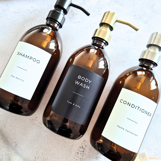 Three brown bottles labeled 'Shampoo', 'Body Wash', and 'Conditioner' on a light background.