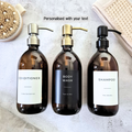 Three brown bottles labeled 'Conditioner', 'Body Wash', and 'Shampoo' on a textured surface.