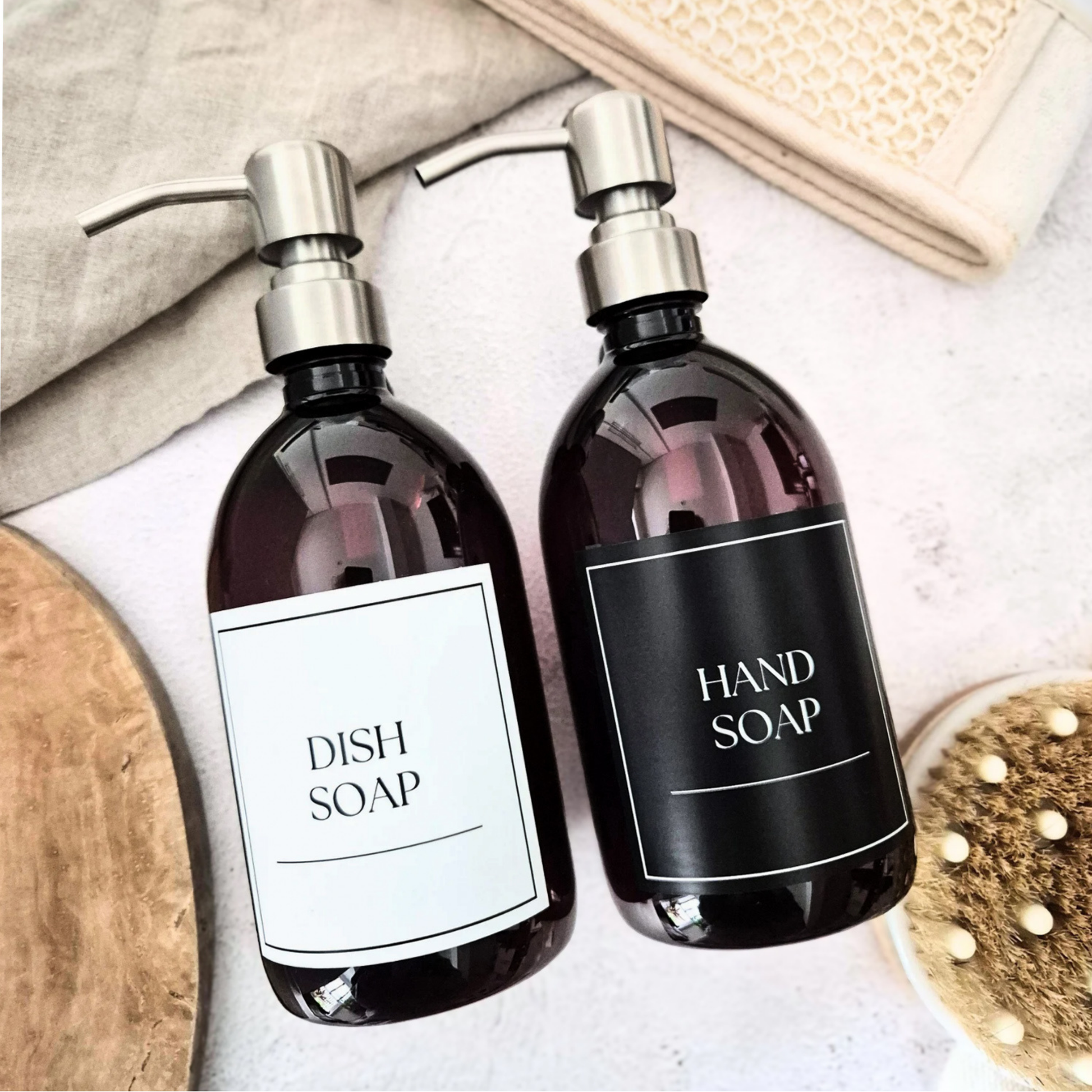 Two refill bottles of dish soap and hand soap with silver pump dispensers on a light background.