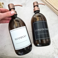 Two brown bottles labeled 'Shampoo' and 'Conditioner' on a light surface.