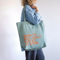 Sage large personalised canvas tote bag with orange text reading Born to Dilly Dally Forced to Work, shoulder carry, printed in our London studio
