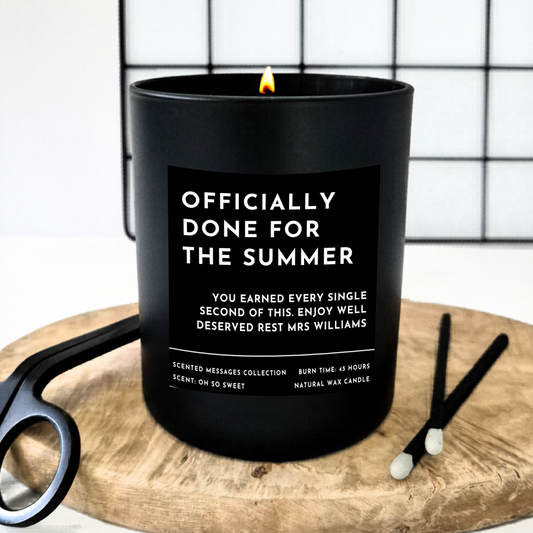 Black candle with text  'Officially done for the summer' and a personalised message underneath 'you earned every single of this. Enjoy well deserved rest Ms Williams'. on a wooden board with matches.