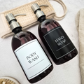 Two amber soap dispensers with black or white label 'Body Wash' and 'Hand Soap' on a textured surface. 