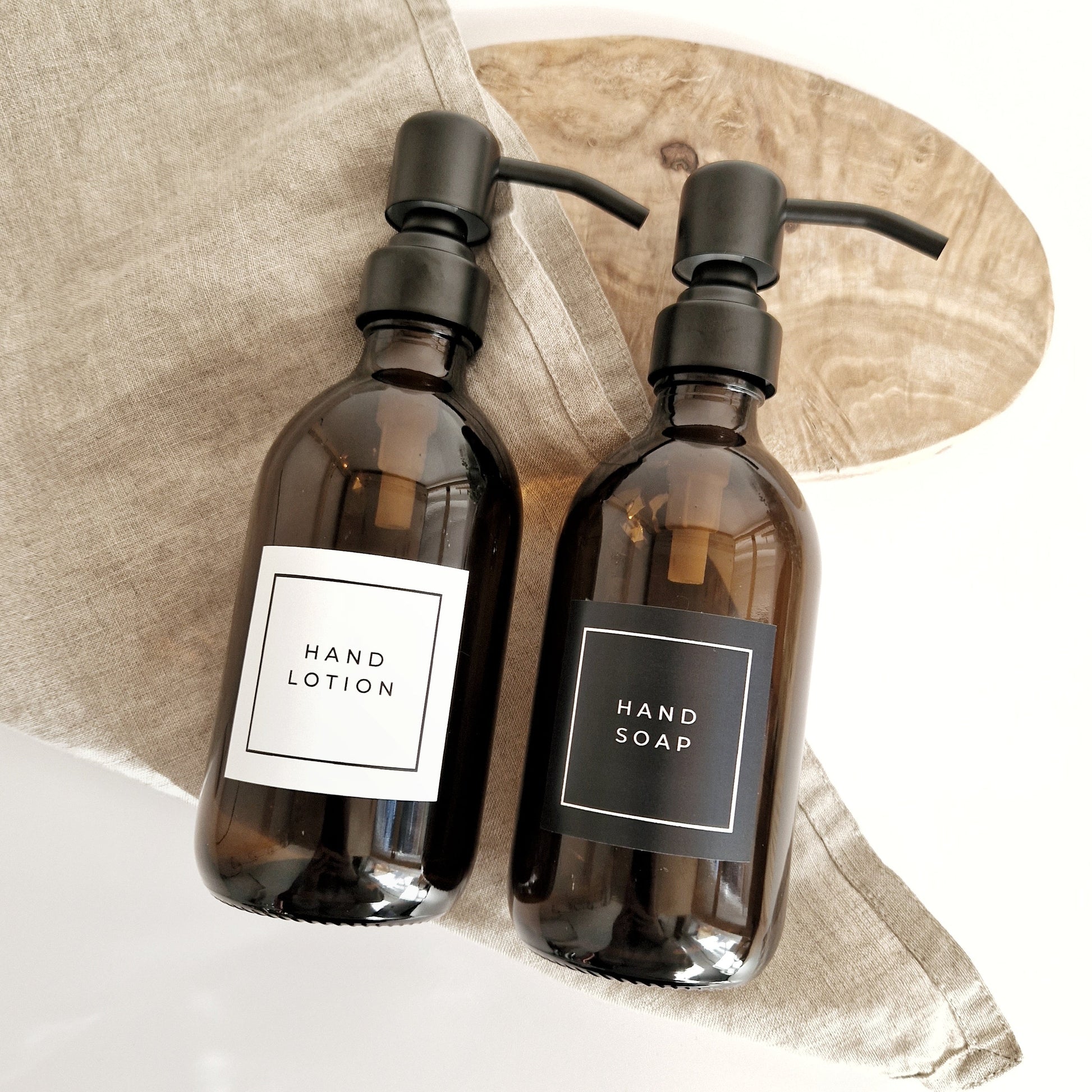Two brown bottles labeled 'Hand Lotion' and 'Hand Soap' on a neutral background.